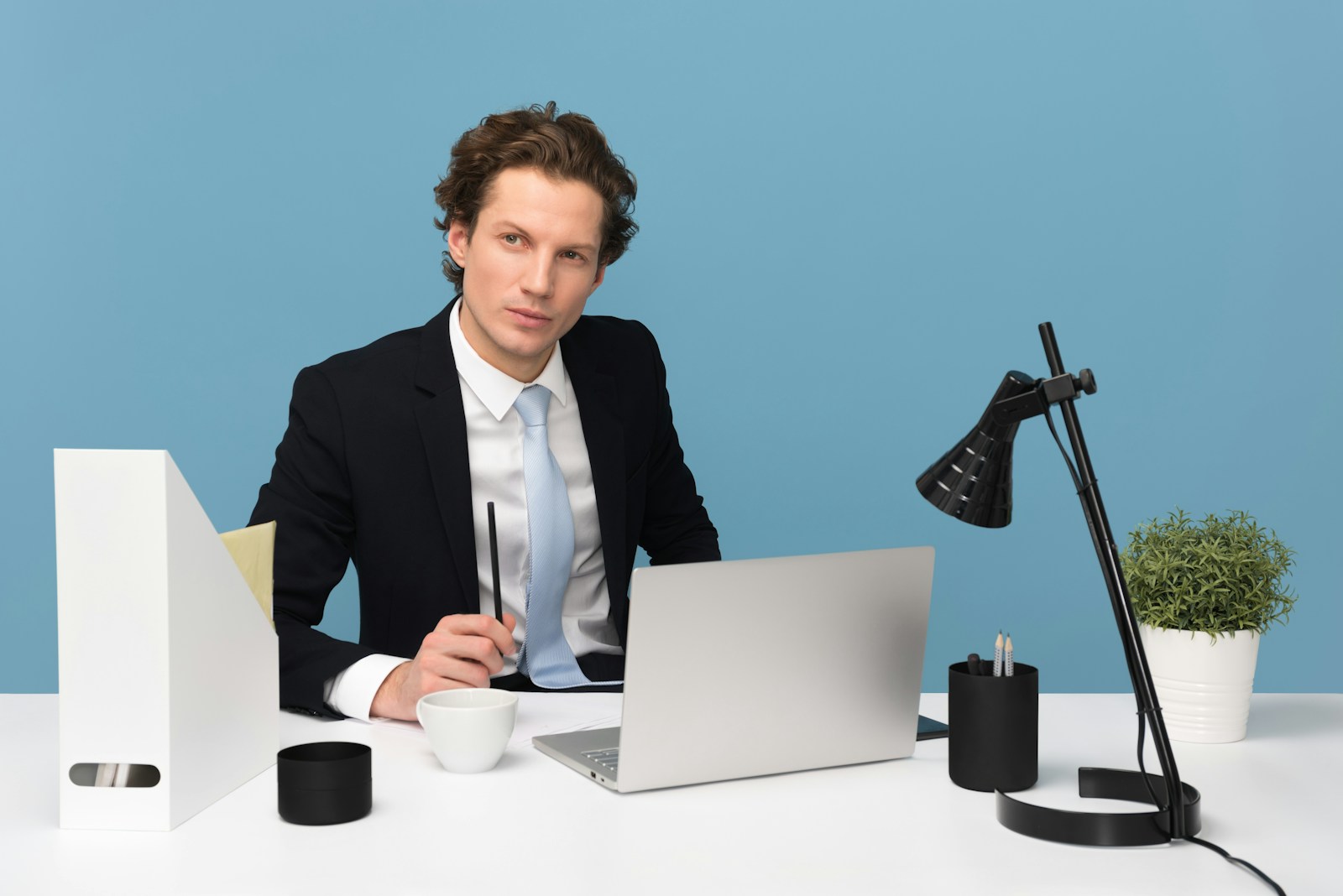 man sitting on chair beside laptop computer and teacup, professional